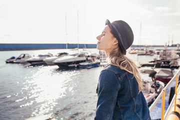 Charming girl tourist enjoys the sunshine standing on the pier and admiring the sea landscape. The...