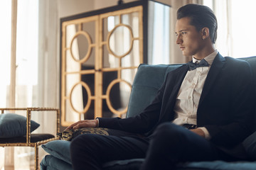 Handsome young luxury man sitting in hotel room. Formal. Groom morning.