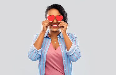 love, valentine's day and charity concept - happy african american young woman with red hearts instead of eyes over grey background