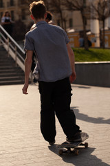 Obraz premium Young guys in stylish clothes ride a skateboard in the park.