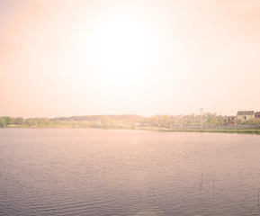 Beautiful sunset over a large lake in the village. Landscape evening summer.