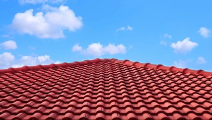 The old red tiles roof slope in pyramid shaped against white clouds and blue sky