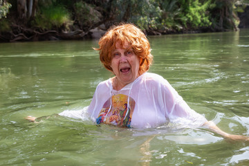 Elder woman is being baptised at Jordan River in the holy land of Israel.