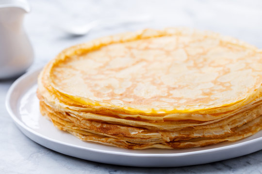 Crepes, thin pancakes with honey on a white plate. Close up.