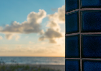 close up of blue tiles on a shower at the beach with the sky and ocean in the background