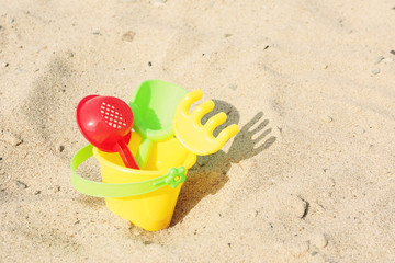 Fototapeta na wymiar Children's toys shovel, rake and sieve in a bucket on the sand...