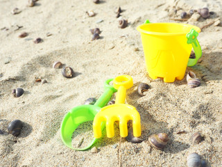 Fototapeta na wymiar Children's toys shovel, rake and bucket on the sand with shells...