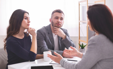 Thoughtful young couple listening to confident financial advisor