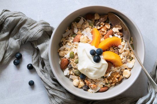 Healthy breakfast; bowl of muesli with sliced peaches and yoghurt.