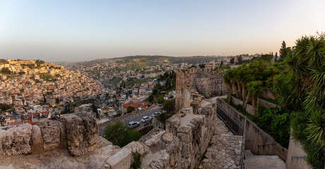 Fototapeta na wymiar Beautiful panoramic view of the Walls of Jerusalem surrounding the Old City with the cityscape in the background during a sunny sunset. Taken near the Jerusalem, Israel.