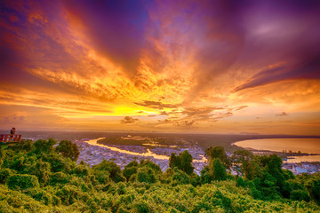 Fototapeta na wymiar Clouds of beautiful color in the summer sunset, Dark Clouds, Natural beautiful cloudscape over the sea with sunlight background and green forest in the foreground at Ban Pak Nam, Chumphon, Thailand.