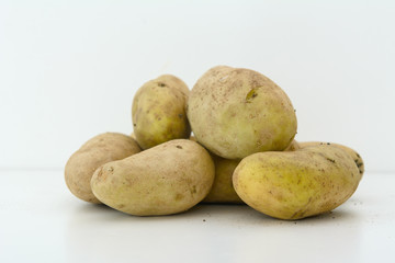 On a white background are a few potatoes. Concept - natural food
