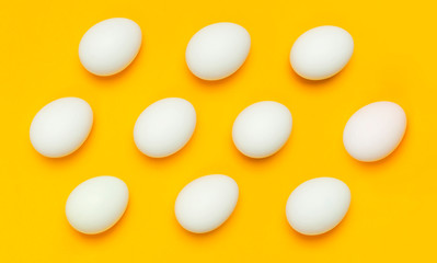 Pattern from White chicken eggs on yellow background top view flat lay copy space. Creative food minimalistic background, Easter. Natural healthy food and organic farming concept.