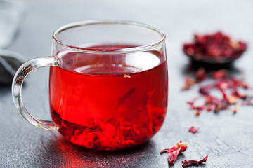 Hibiscus tea in glass cup. Grey background. Close up.