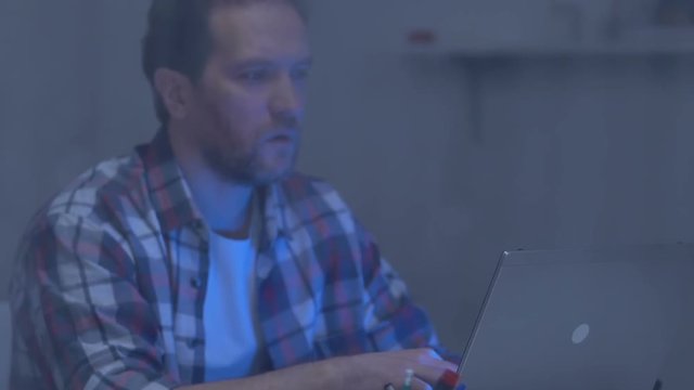Thoughtful male freelance writer having no ideas, working on laptop on rainy day