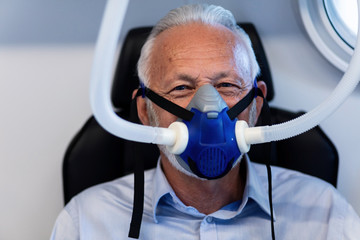 Senior man oxygen mask during treatment in hyperbaric chamber.