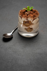 portion of Classic tiramisu dessert in a glass on concrete background