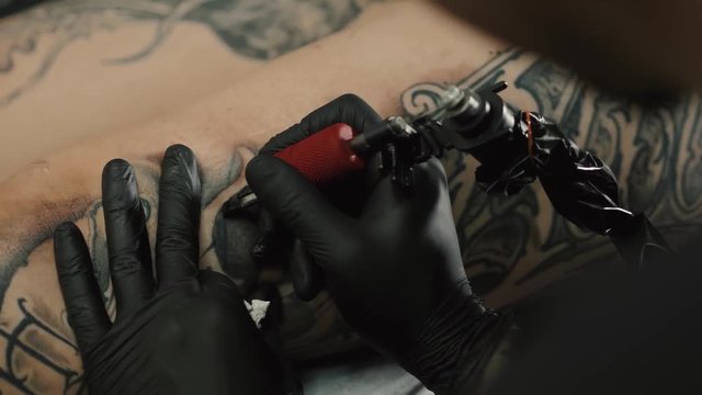 Professional artist making tattoo in salon. Close-up view of male hand making tattoo closeup macro