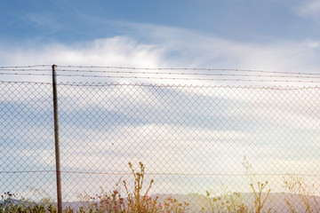 Wire fence with a blue sky with clouds