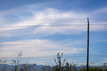 Wire fence with a blue sky with clouds