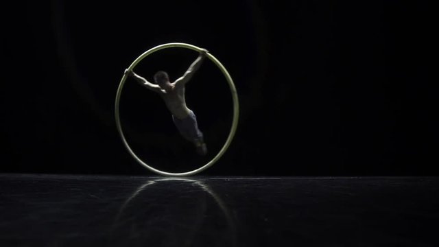 Muscular circus artist in the Cyr Wheel doing difficult tricks slow motion