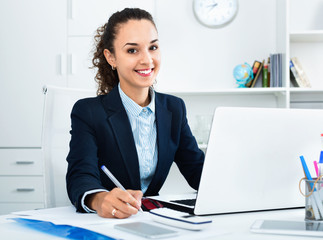 Business lady sitting at office desk with laptop - obrazy, fototapety, plakaty