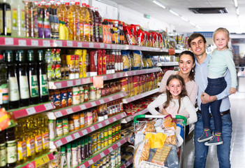 Couple with children buying food in hypermarket.