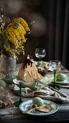 Orthodox Easter table setting with caramel easter cottage cheese cake on wooden light green board on grey wooden table