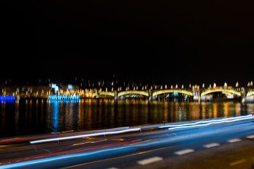 Fototapeta na wymiar abstract glowing lights of a night city with a bridge, photograph blurred on long exposure