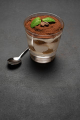 portion of Classic tiramisu dessert in a glass on concrete background
