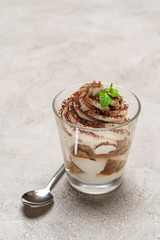 portion of Classic tiramisu dessert in a glass on concrete background