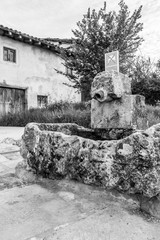 Old water fountain with a weathered stone sink at Barrios de Colina, Province of Burgos, Castilla y Leon, Spain on the Way of St. James, black and white photography