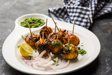 Tandoori aloo are roasted potatoes with Indian spices. It's a party appetiser served with green chutney. selective focus