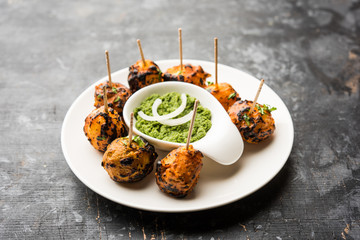 Tandoori aloo are roasted potatoes with Indian spices. It's a party appetiser served with green chutney. selective focus