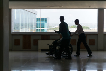 Fototapeta premium Silhouette of flight crew helps sick passengers using a wheelchair