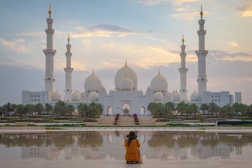 Gordijnen A single lady woman looking at an axial view of the Great Mosque of Abu Dhabi at sunset © Dan Tiégo