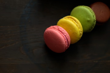 Multi-colored macaroons on a wooden tray. Pink, yellow and green macaroon.