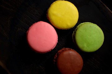 Multi-colored macaroons on a wooden tray. Pink, yellow and green macaroon.