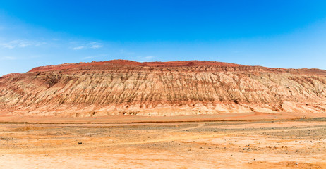 Fototapeta premium Flaming mountains, Turpan, Xinjiang, China: these intense red arid mountains similar to scorching flames appear in the Chinese epic “Journey to the west”. Turpan is an ancient oasis on the Silk Road