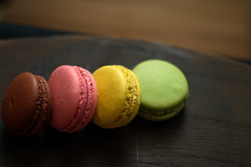Multi-colored macaroons on a wooden tray. Pink, yellow and green macaroon.