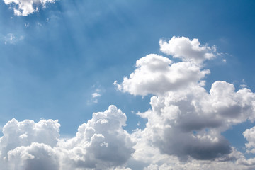 View of the sky of blue color and white clouds through which the sun's rays make their way