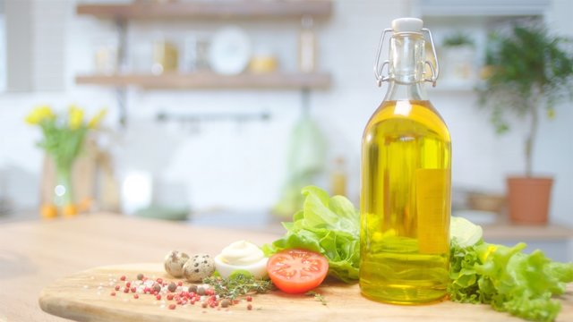 Commercial packshot with olive oil and fresh greens at the table