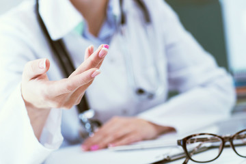 Female doctor explaining patient symptoms or asking a question as they discuss together in a consultation. Just hands over the table.