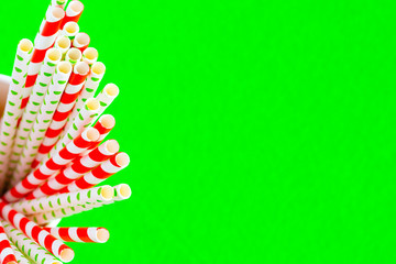 Red straws for juice in a paper cup on a green background. from the left