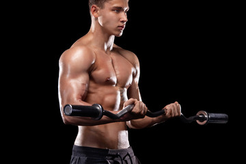 Strong muscular bodybuilder athletic man pumping up muscles with barbell on black background....