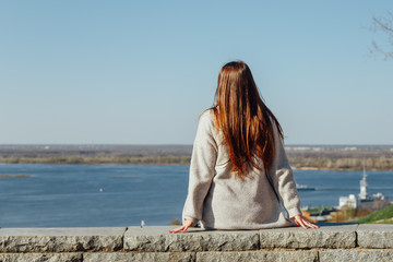 Beautiful young girl sitting on the Volga river embankment