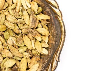 Closeup of lot of whole true cardamom pod in old iron bowl flatlay isolated on white background