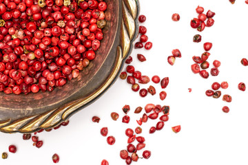 Lot of whole dry peruvian pink pepper in old iron bowl flatlay isolated on white background