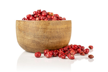 Lot of whole dry peruvian pink pepper in a wooden bowl isolated on white background