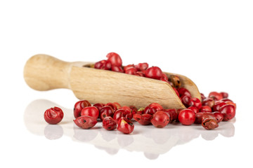Closeup of lot of whole peruvian pink pepper with wooden scoop isolated on white background